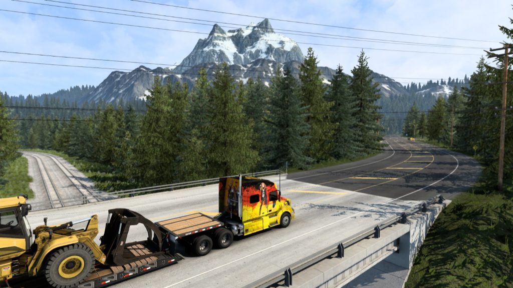 ATS Volvo truck hauling a wheel loader on a highway in western Canada