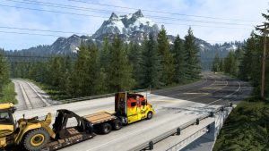 ATS Volvo truck hauling a wheel loader on a highway in western Canada